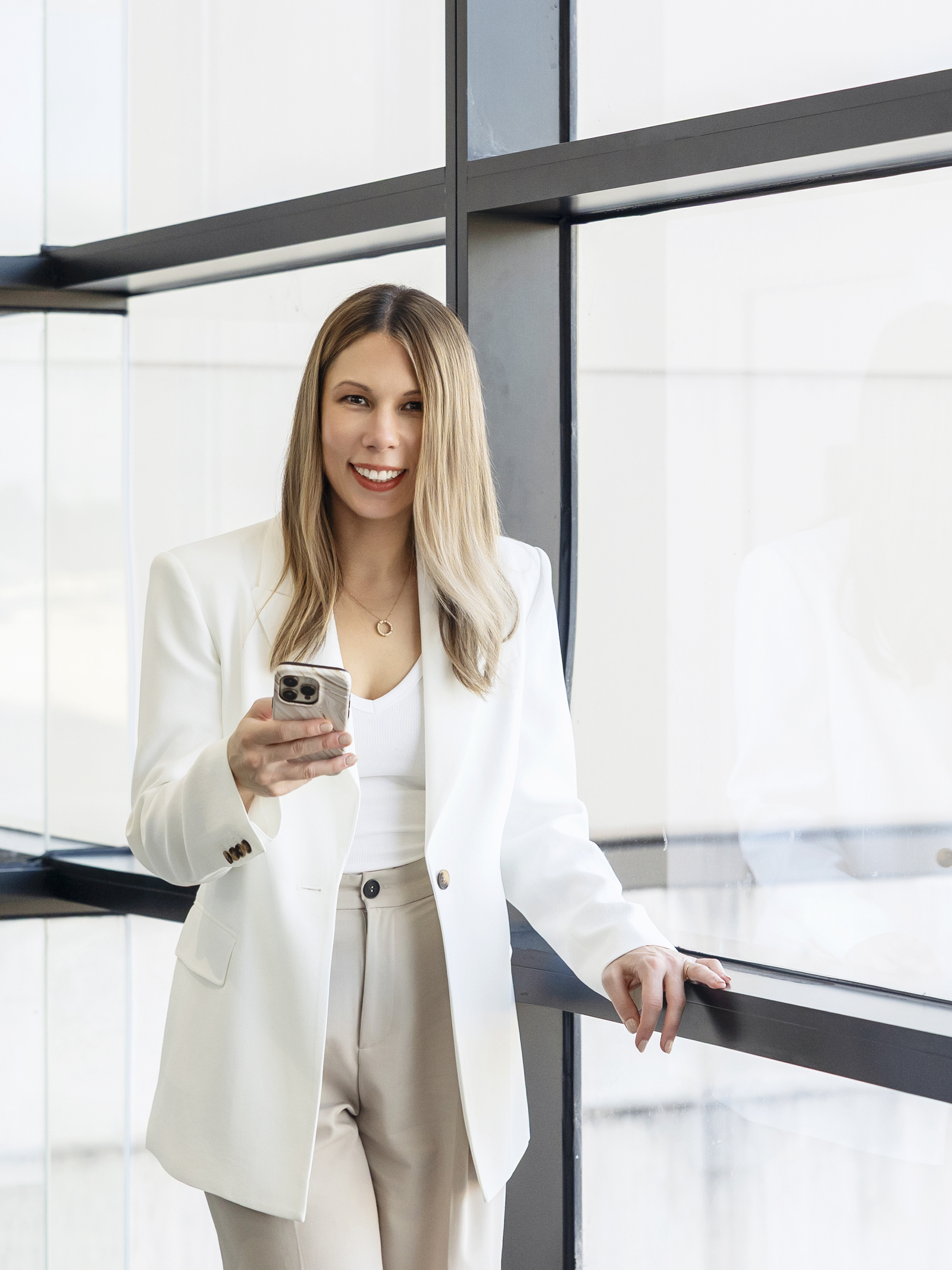 Jacquelina standing by a window holding her phone